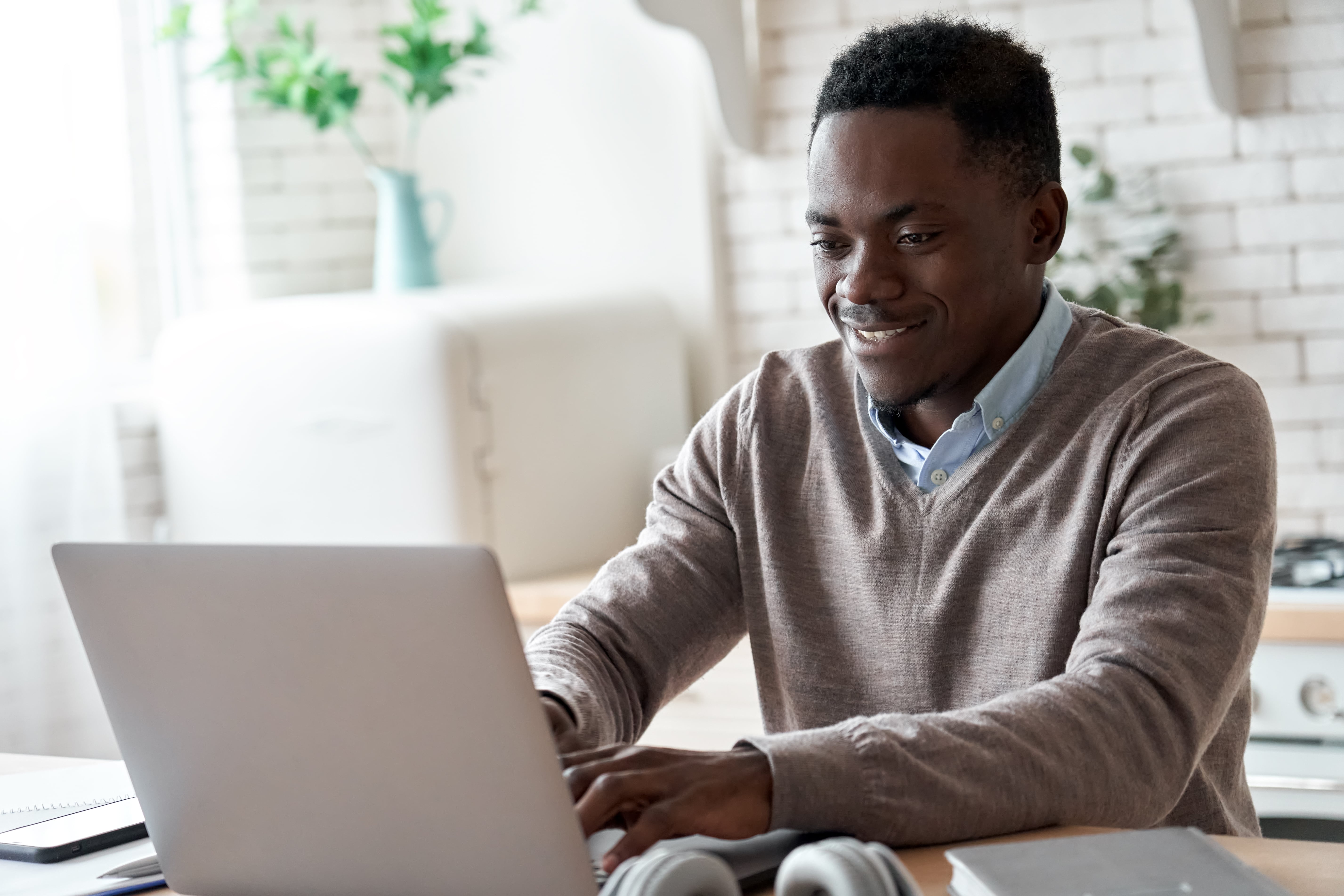 African American teacher sitting at desk doing professional learning on his laptop