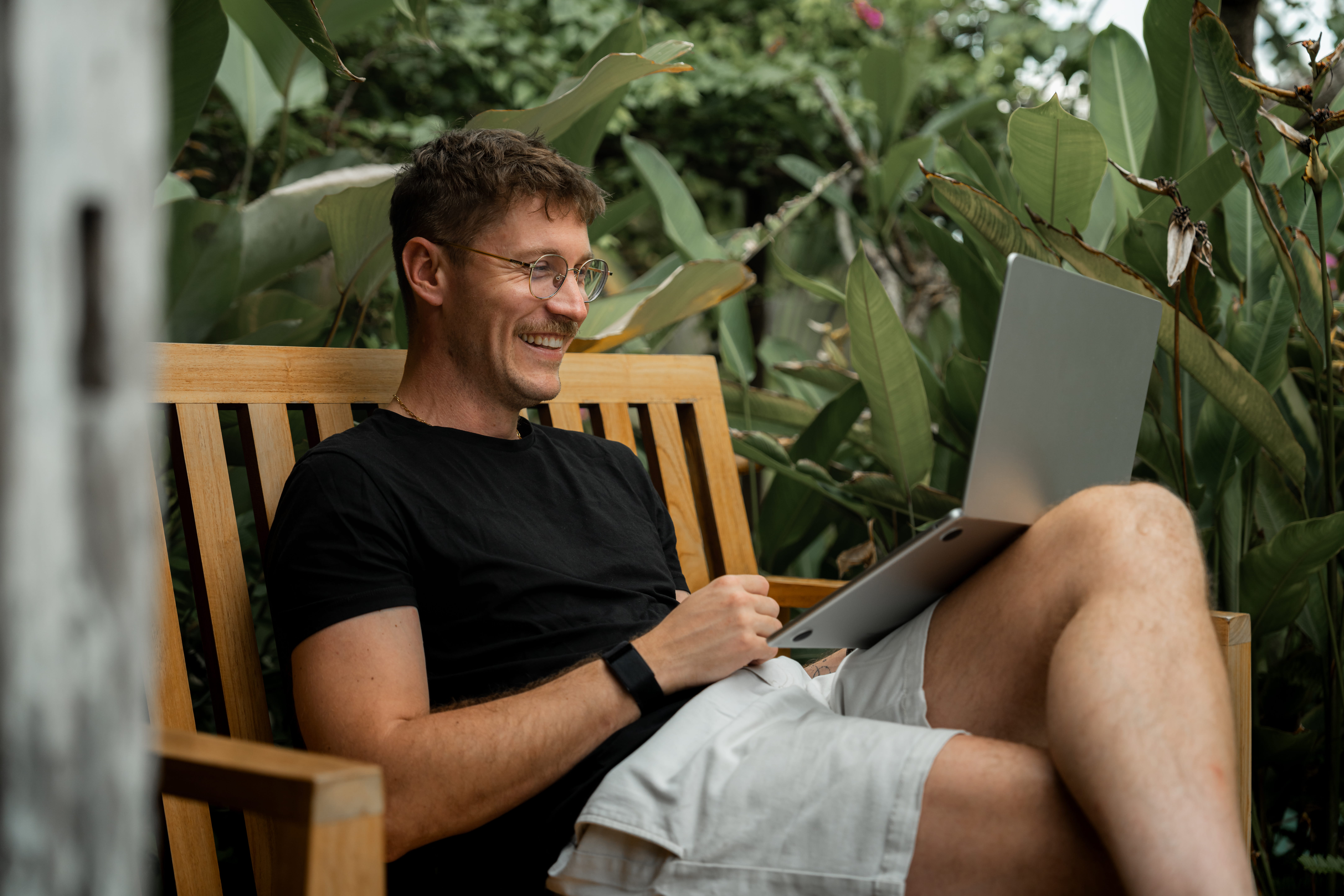 Male teacher sitting on a bench outdoors using a laptop to learn about instructional strategies during the TeachersFirst book study.